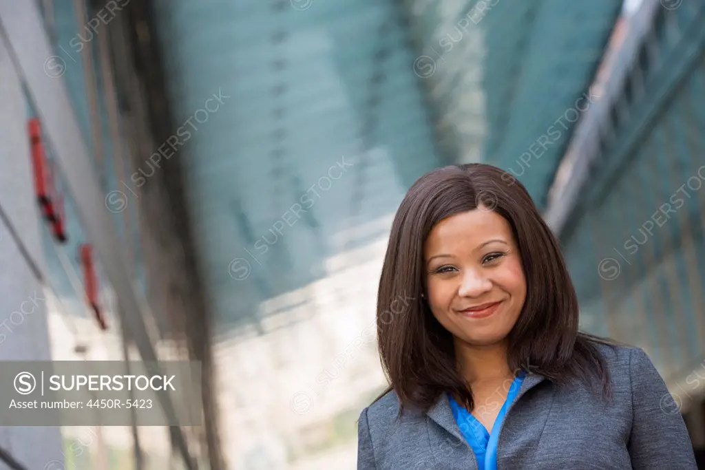 Summer in the city. Businesspeople outdoors, on the go. A woman in a grey suit with a bright blue shirt.