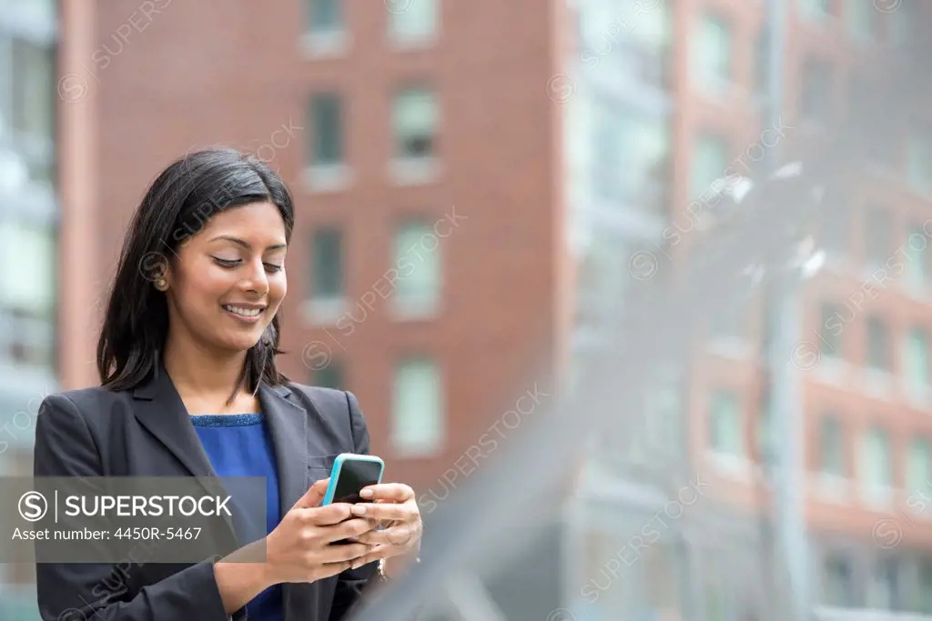 Business people out and about in the city. A young woman in a blue dress and grey jacket.