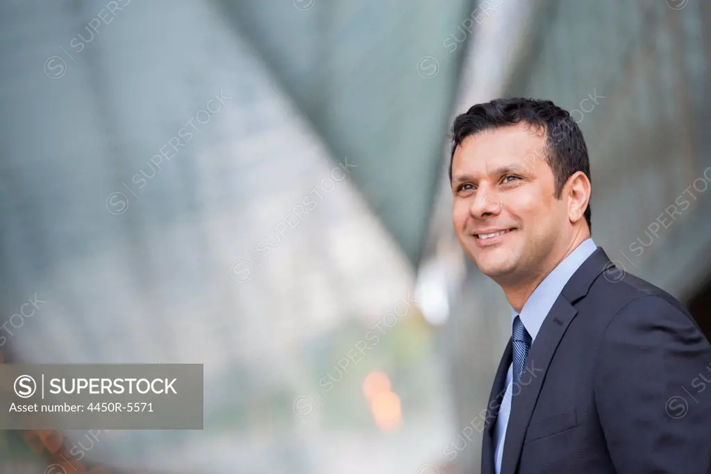 Business people outdoors, keeping in touch while on the go. A Latino businessman in business clothes.