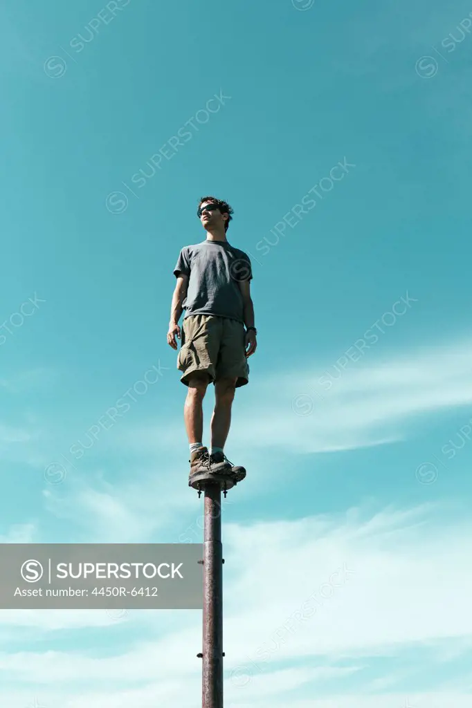 Man standing and balancing on metal post, looking towards expansive sky, Surprise Mountain, Alpine Lakes Wilderness, Mt. Baker-Snoqualmie national forest.