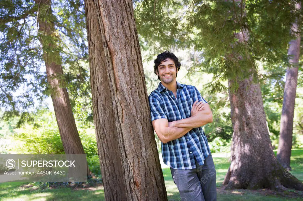 A farm growing and selling organic vegetables and fruit. A man leaning against a tree.