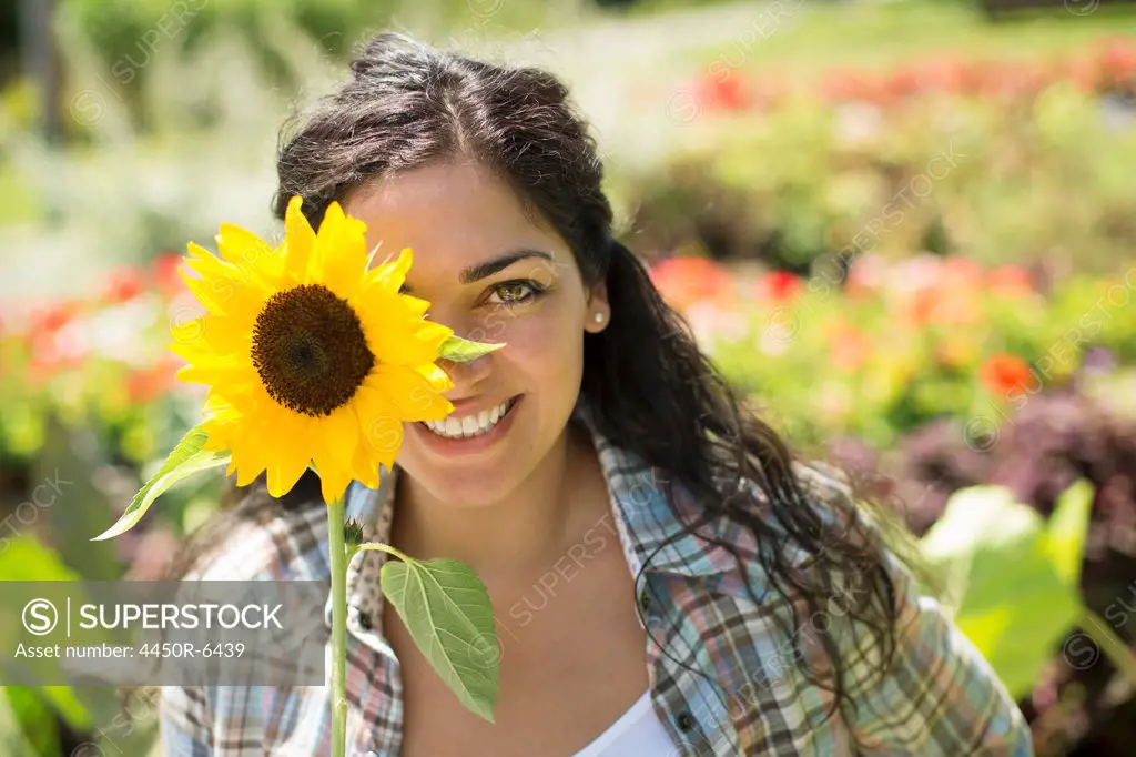 A farm growing and selling organic vegetables and fruit. A woman holding a large sunflower.