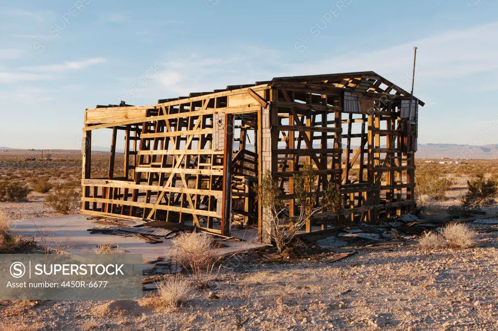 A small abandoned building in the Mojave desert landscape.