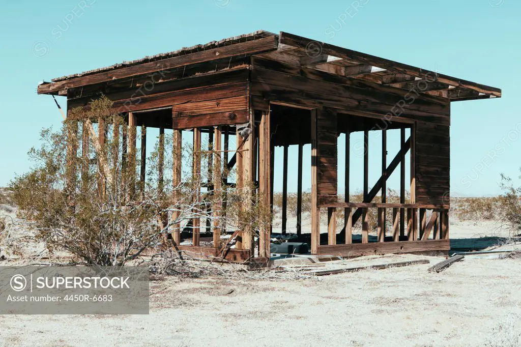 A small abandoned building in the Mojave desert landscape.