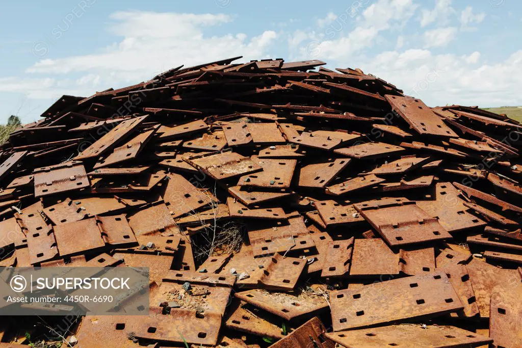 A large pile of rusty plates, used for railroad construction. Discarded or piled up for recycling.