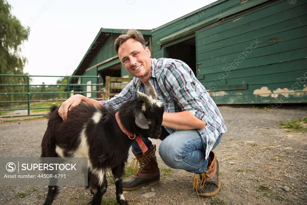 An organic farm in the Catskills. A man with a small goat on a halter.