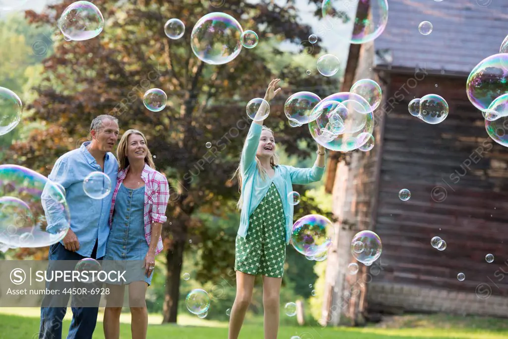 A family sitting on the grass outside a bar, blowing bubbles and laughing.