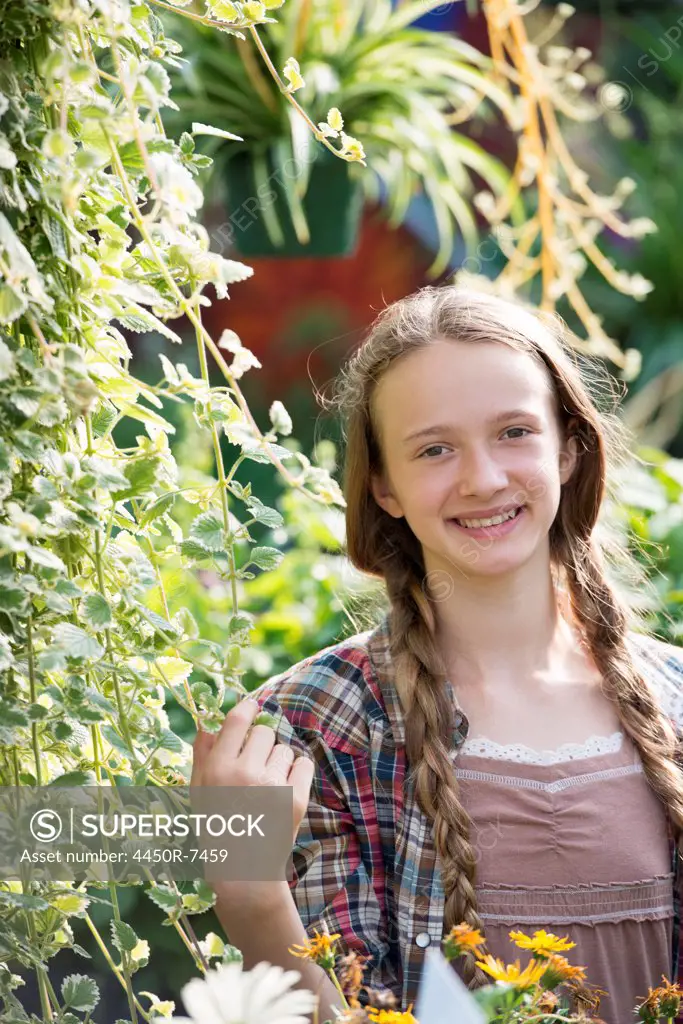 Summer on an organic farm. A young girl in a plant nursery full of flowers.
