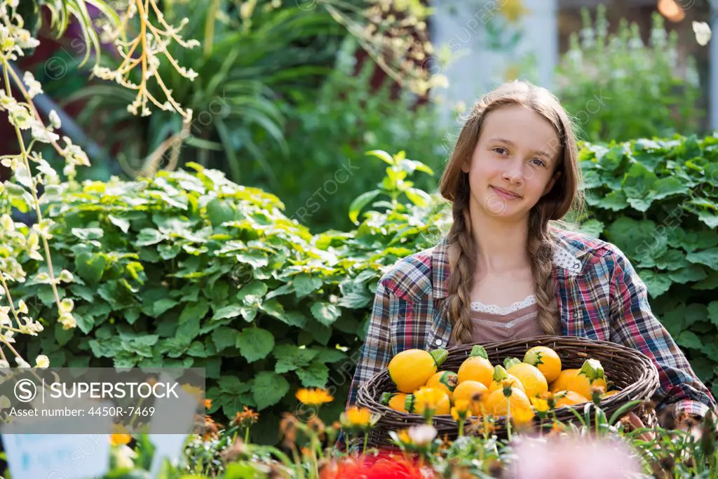 Summer on an organic farm. A girl holding a basket of fresh squash vegetables.