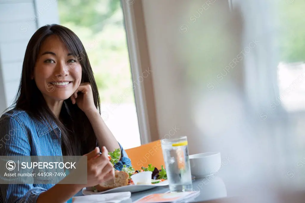 A woman seated eating in a cafe.