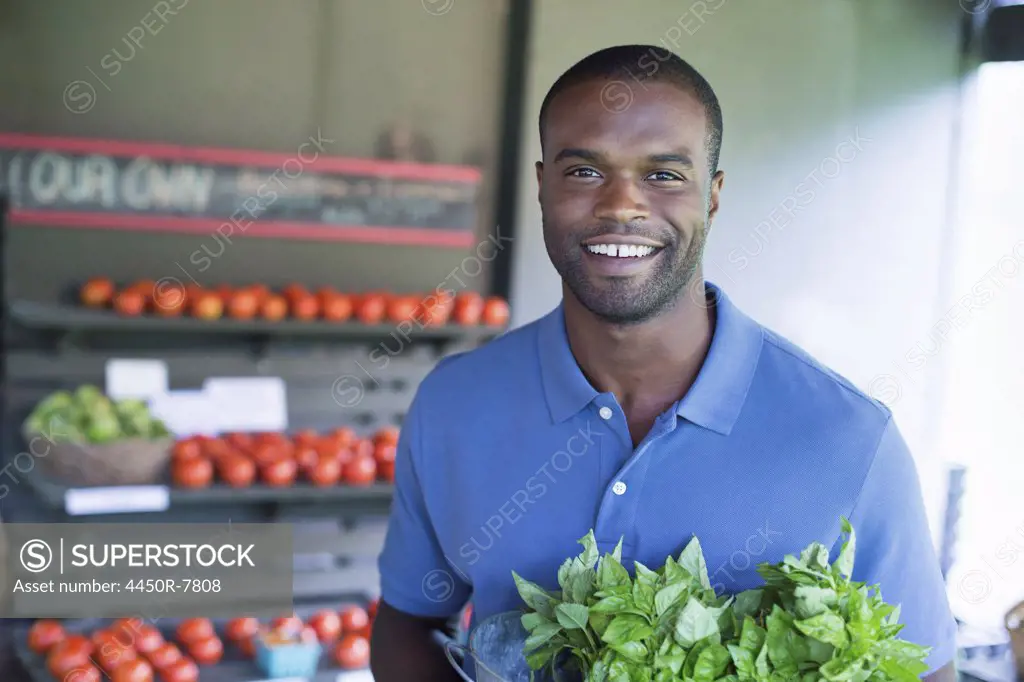 An organic fruit and vegetable farm. A man carrying vegetables.