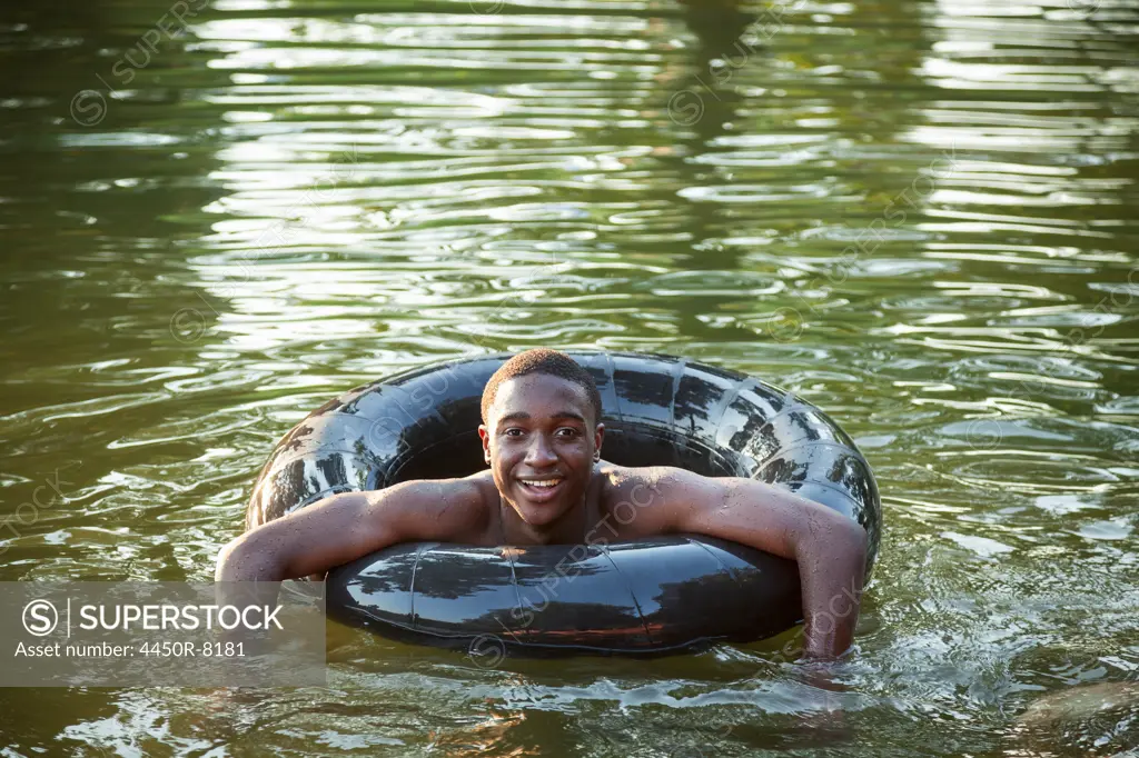A boy floating in the water using a tyre swim float. Maryland, USA. 7/1/2012