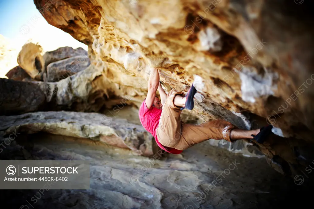 A man free climbing on the overhang of a rock face, with minimum equipment. USA, 10/10/2010
