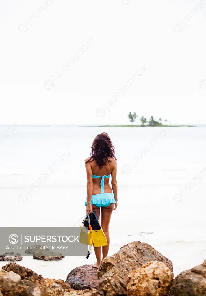 A young woman holding snorkelling gear on the Samana Peninsula in the Dominican Republic. Samana Peninsula, Dominican Republic. 4/6/2011