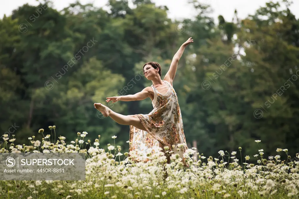 A woman dancing in a field of wild flowers. Woodstock, New York, USA. 4/26/2012