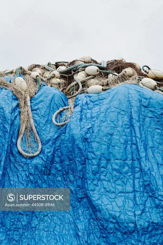 A blue tarpaulin covering stacked commercial fishing nets on the dockside at Fisherman's Wharf, Seattle. Seattle, Washington, USA. 5/31/2012