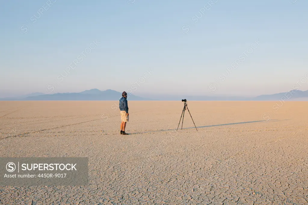 Man with camera and tripod on the flat saltpan or playa of Black Rock desert, Nevada. Black Rock Desert, Nevada, USA. 8/8/2012