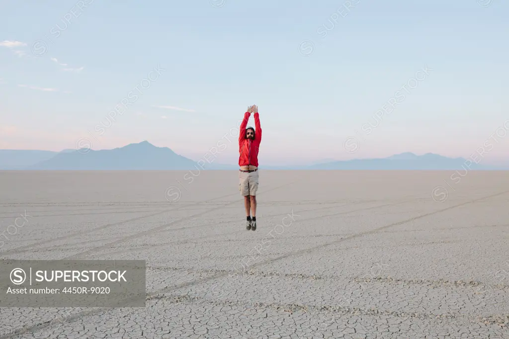 A man jumping in the air on the flat desert or playa or Black Rock Desert, Nevada. Black Rock Desert, Nevada, USA. 8/8/2012