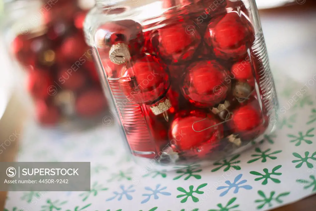 Red glass ball Christmas ornaments in glass jars on a tabletop. Woodstock, New York, USA. 9/9/2012
