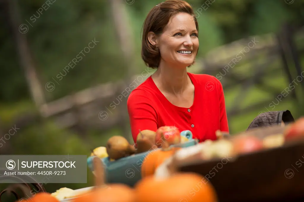 A woman in a red shirt, at a harvest table outdoors. Woodstock, New York, USA. 9/9/2012