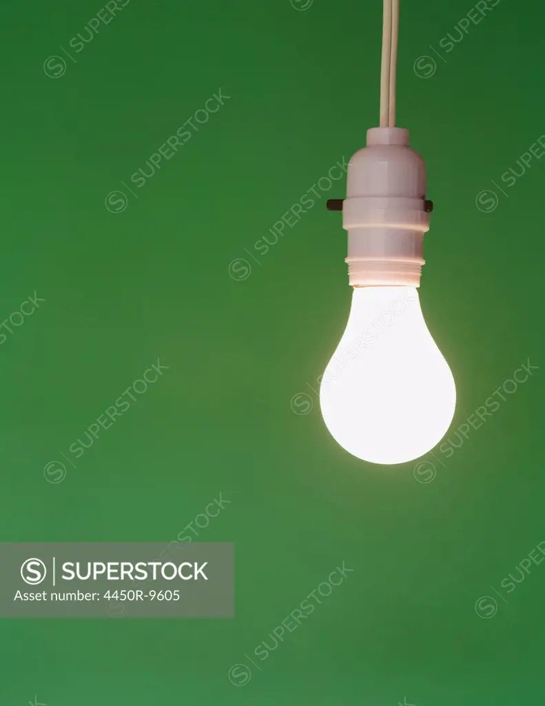 Traditional glass light bulb and switch with a white electric flex. Green background. 10/16/2012