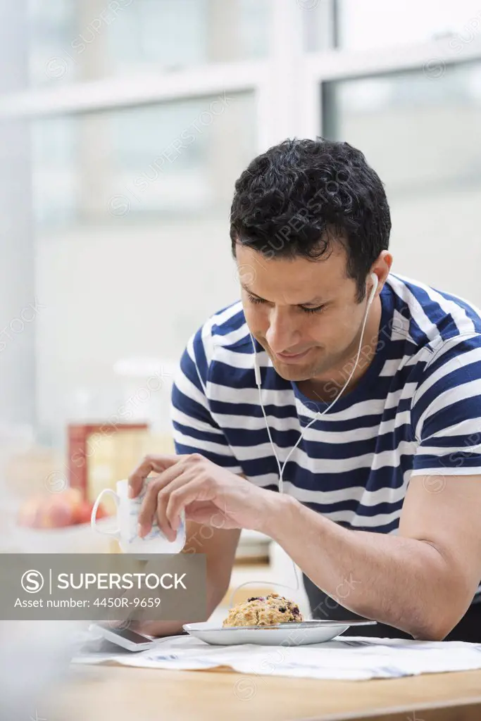 An office or apartment interior in New York City. A man in a striped tee shirt leaning on the breakfast bar. New York City, USA