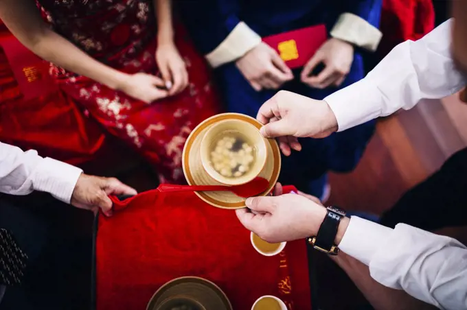 High angle close up of a ritual at a Chinese wedding ceremony, people passing a bowl of soup.