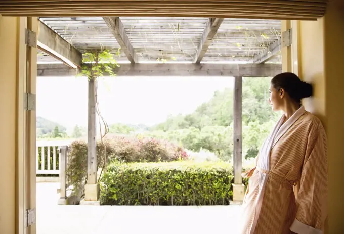 Woman in bathrobe looking out over Napa Valley, California at a luxury spa