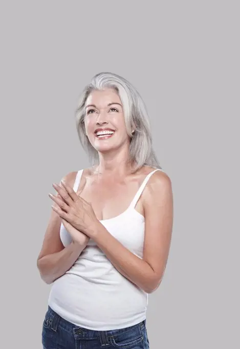 Attractive mature Caucasian woman with silver grey hair in a white tank top, bare shoulders.