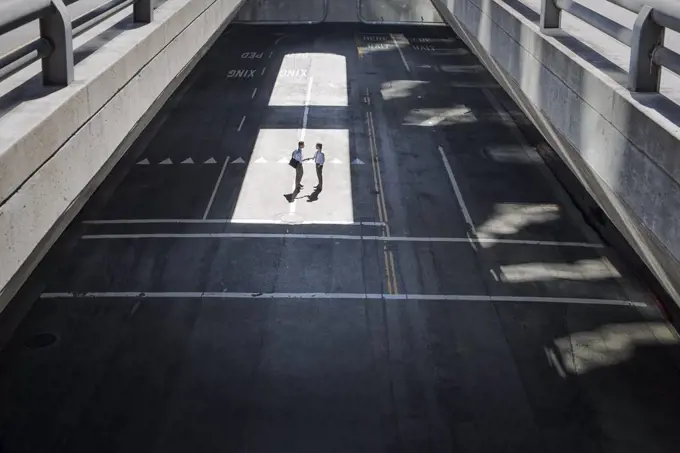 View from above onto a city plaza and two men walking from shadow into sunlight.