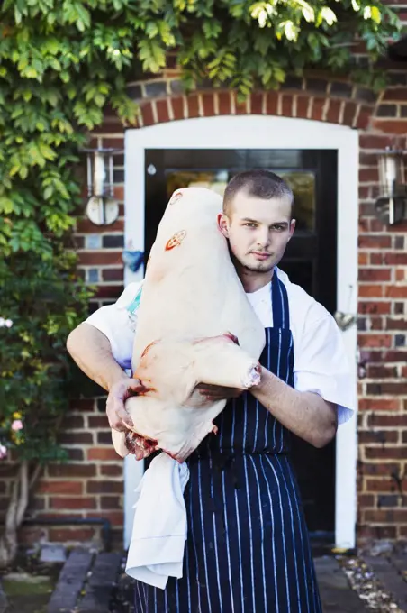 The Red Lion village public house chef carrying a large carcass of an animal, meat for the restaurant.