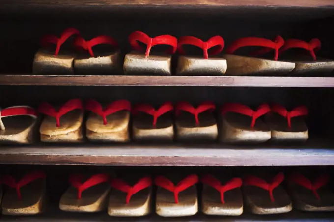 Rows of traditional wooden sandals with thick soles and red straps worn by geisha, okobo or geta.