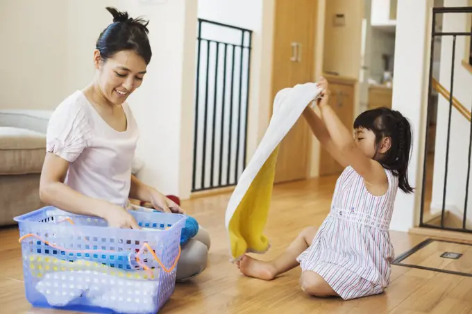 Family home. A woman and her daughter folding clean laundry.