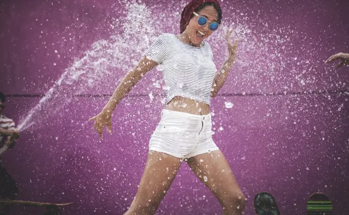 A young woman being sprayed with water.