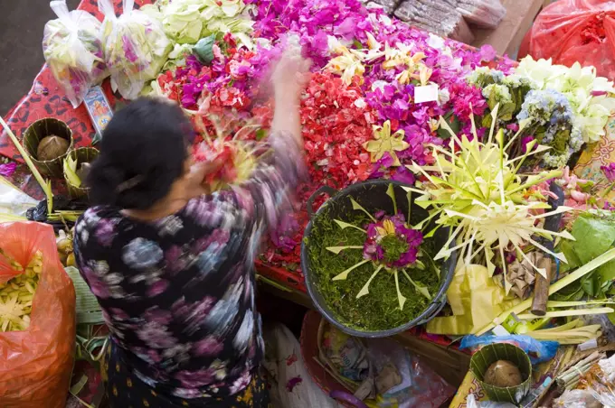 High angle view of woman at Asian flower market, flower arrangements and heaps of colourful blossoms.