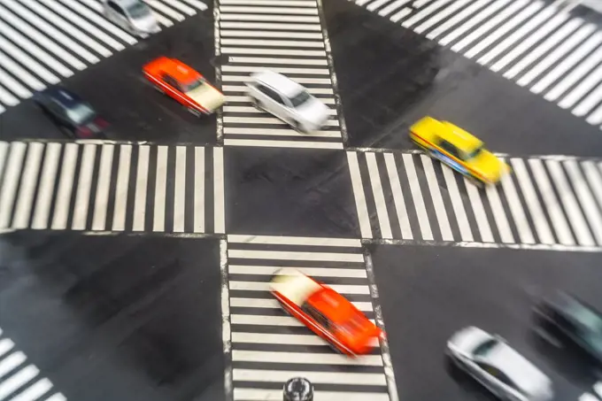 High angle view of cars driving on urban street across pedestrian crossings.