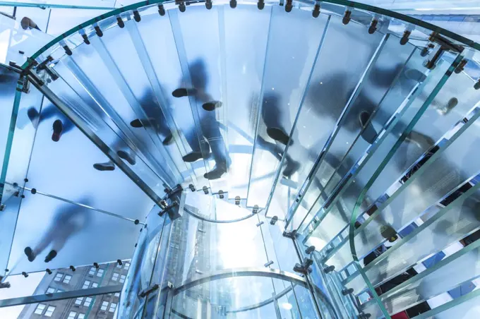 Low angle view of people walking on transparent spiral staircase.