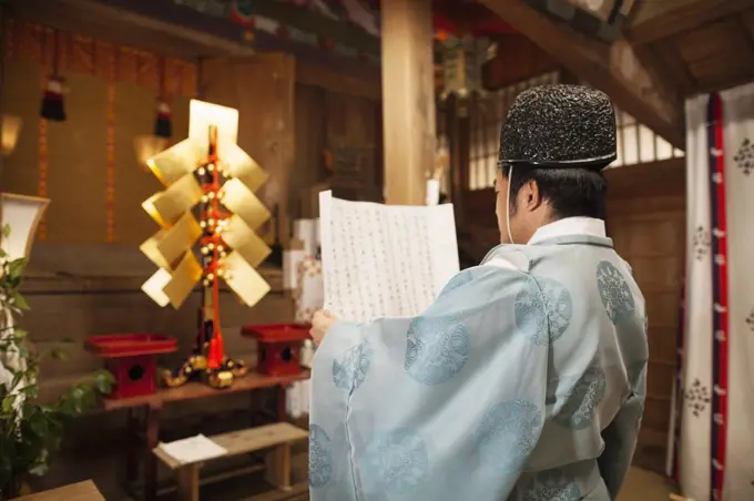 Rear view of priest holding scroll at Shinto Sakurai Shrine, Fukuoka, Japan.