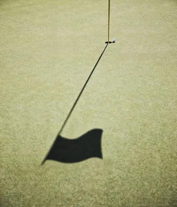Shadow of a golf flag on the green of a golf course.