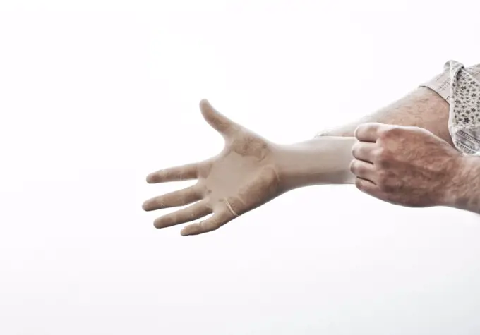 A closeup of a hand pulling on a medical examination glove.