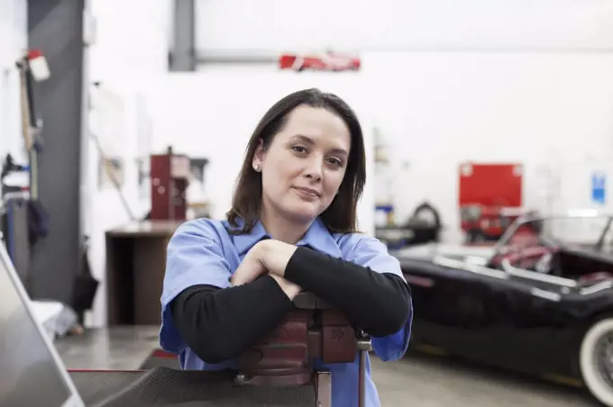 A portrait of a caucasian female mechanic in a car repair shop.