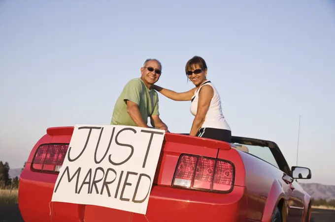 A senior couple "just married" sitting in a convertible sports car in eastern Washington State, USA.