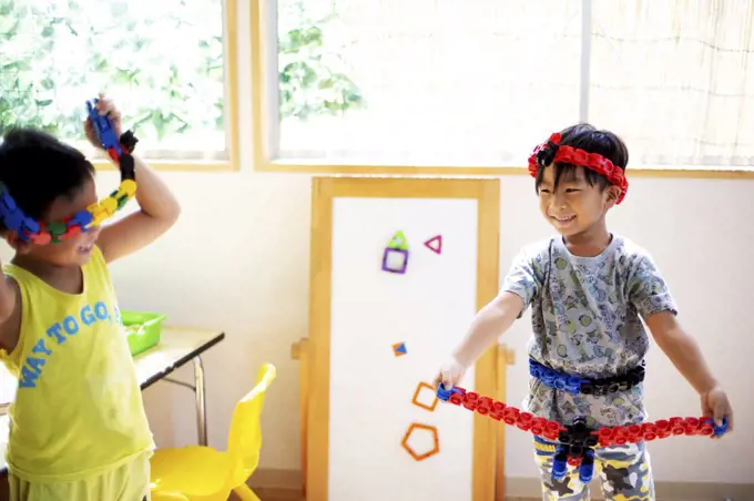 Two smiling children playing with toys in a Japanese preschool.