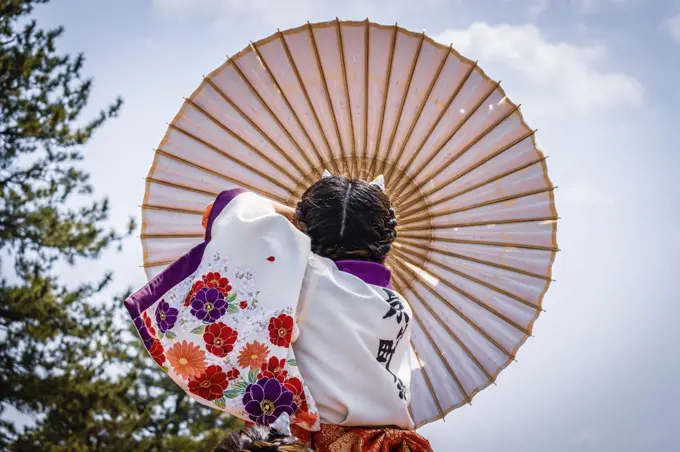 Japanese girl carrying traditional umbrella during a spring festival.