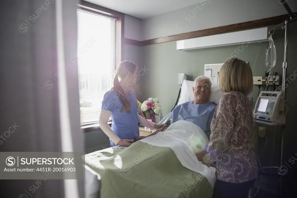 Nurse and wife talking to patient in hospital room