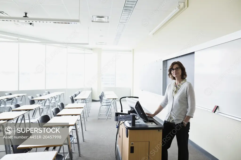 Portrait smiling professor preparing at computer in classroom