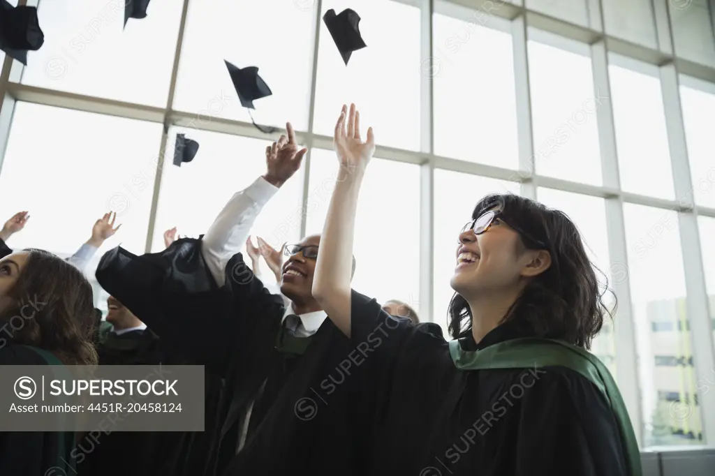 Enthusiastic college graduates throwing mortarboards overhead