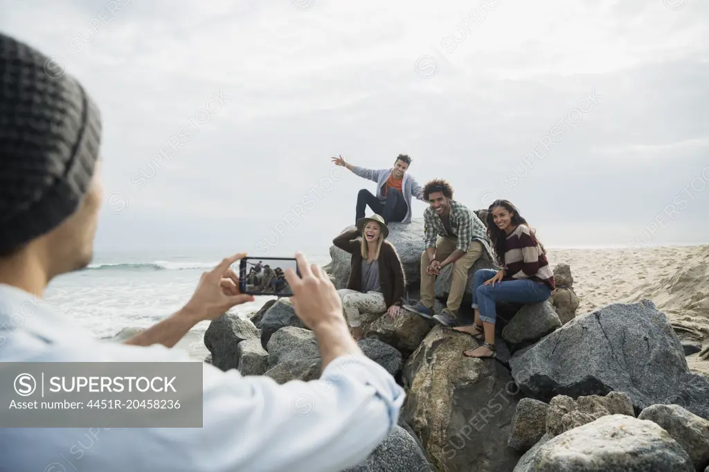 Friends posing for photograph on beach rocks