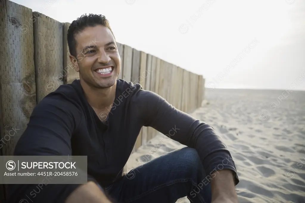 Enthusiastic man smiling at beach wall