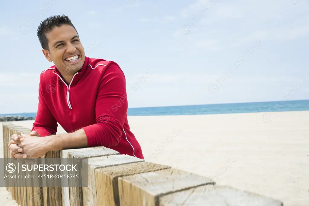 Enthusiastic man leaning against beach wall